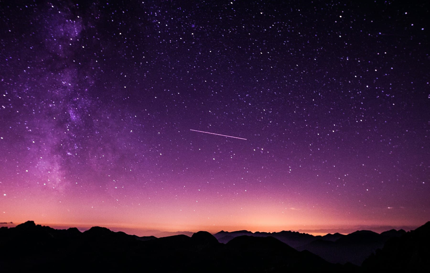 A night sky over mountain ridges.